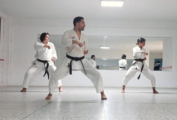 Karatekas adultos y adolescentes entrenando secuencias de movimientos