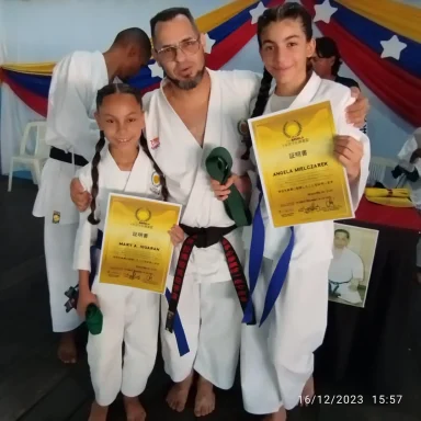Instructor de karate y alumnas con certificados y cinturones de grado luego de examen