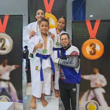 Alumnos en podio lucen medallas junto a su profesor